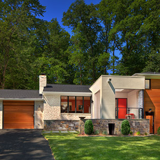 mid century modern style tan home with bright orange accents for the front and garage door