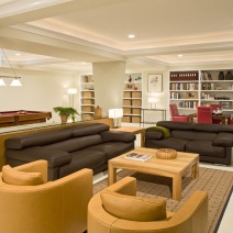 remodeled basement with brown couches and a pool table