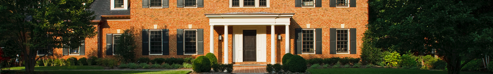 Exterior of a brick colonial home with black shutters