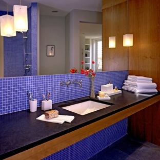 updated bathroom with deep blue tile behind the vanity