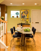 green dining room with a light wood table and four black chairs