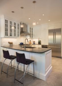 updated white kitchen with black countertops and white cabinets and backsplash