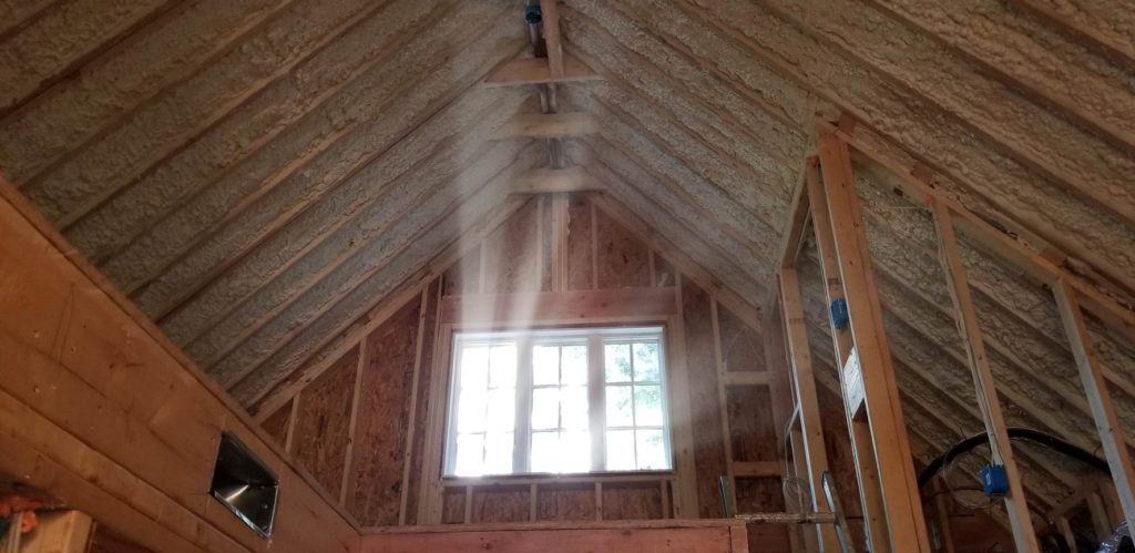Attic of a home with new spray foam insulation applied by Wentworth Studios.