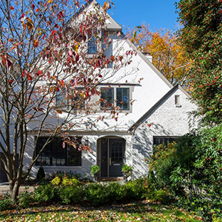 beautiful white brick home with greenery