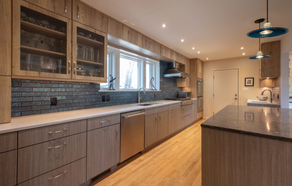 updated kitchen by Wentworth Studio with light wood cabinets and green brick backsplash