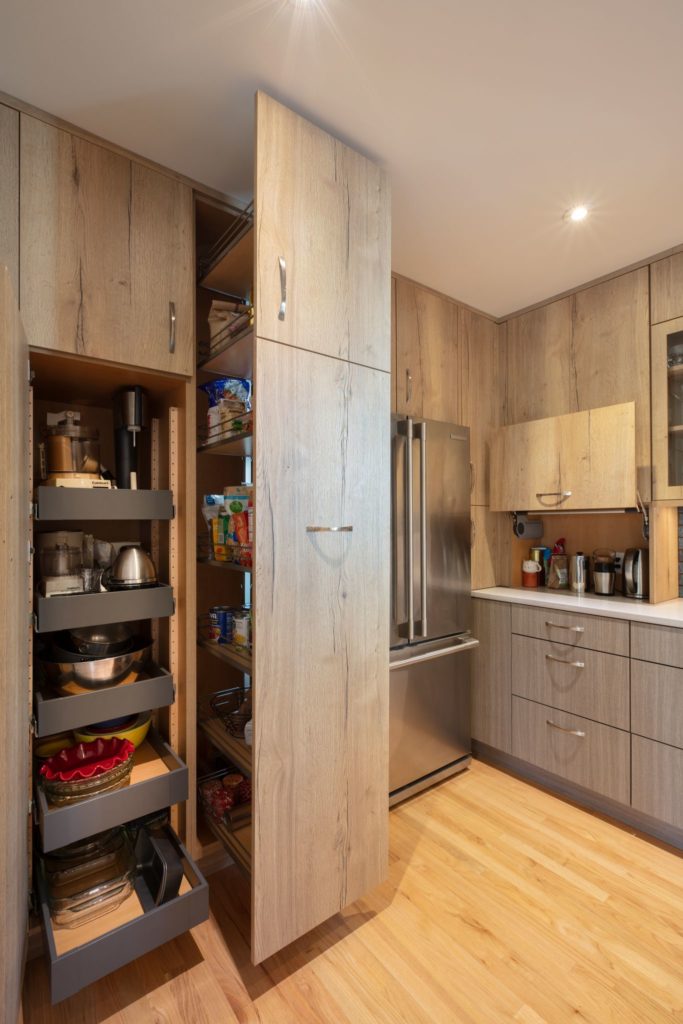 kitchen with light wood floor to ceiling cabinets that slide out