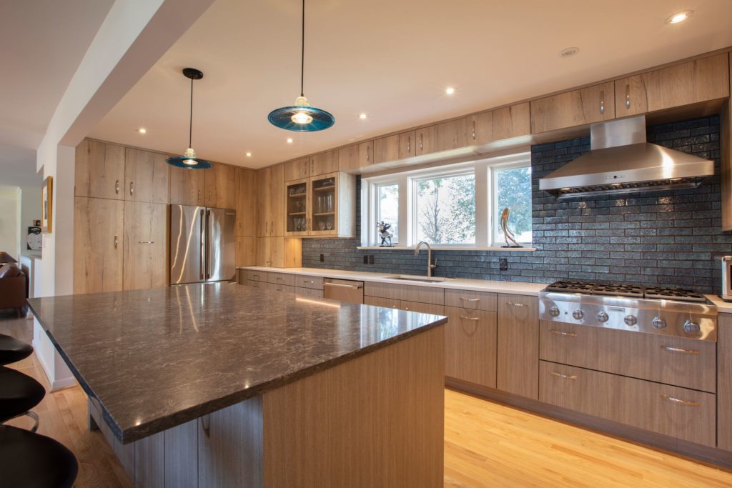 updated kitchen by Wentworth Studio with light wood cabinets and green brick backsplash