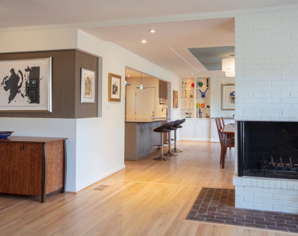 kitchen view with two black leather barstools and white brick fireplace