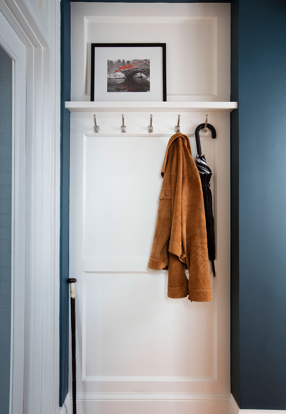a coat rack with coat and umbrella hanging on it