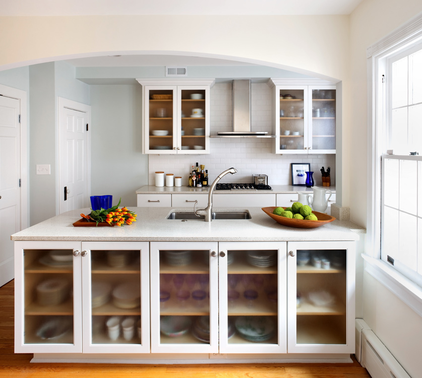 a white kitchen with glass cabinets built into the counters