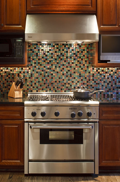 a stove top oven with range and colorful tile backsplash