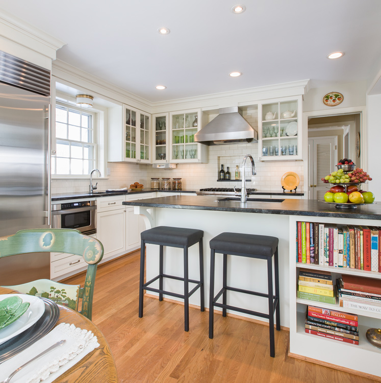 a kitchen with two stools at an island with built in cookbook shelf