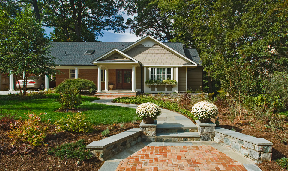 tan and brick home with a stone walkway
