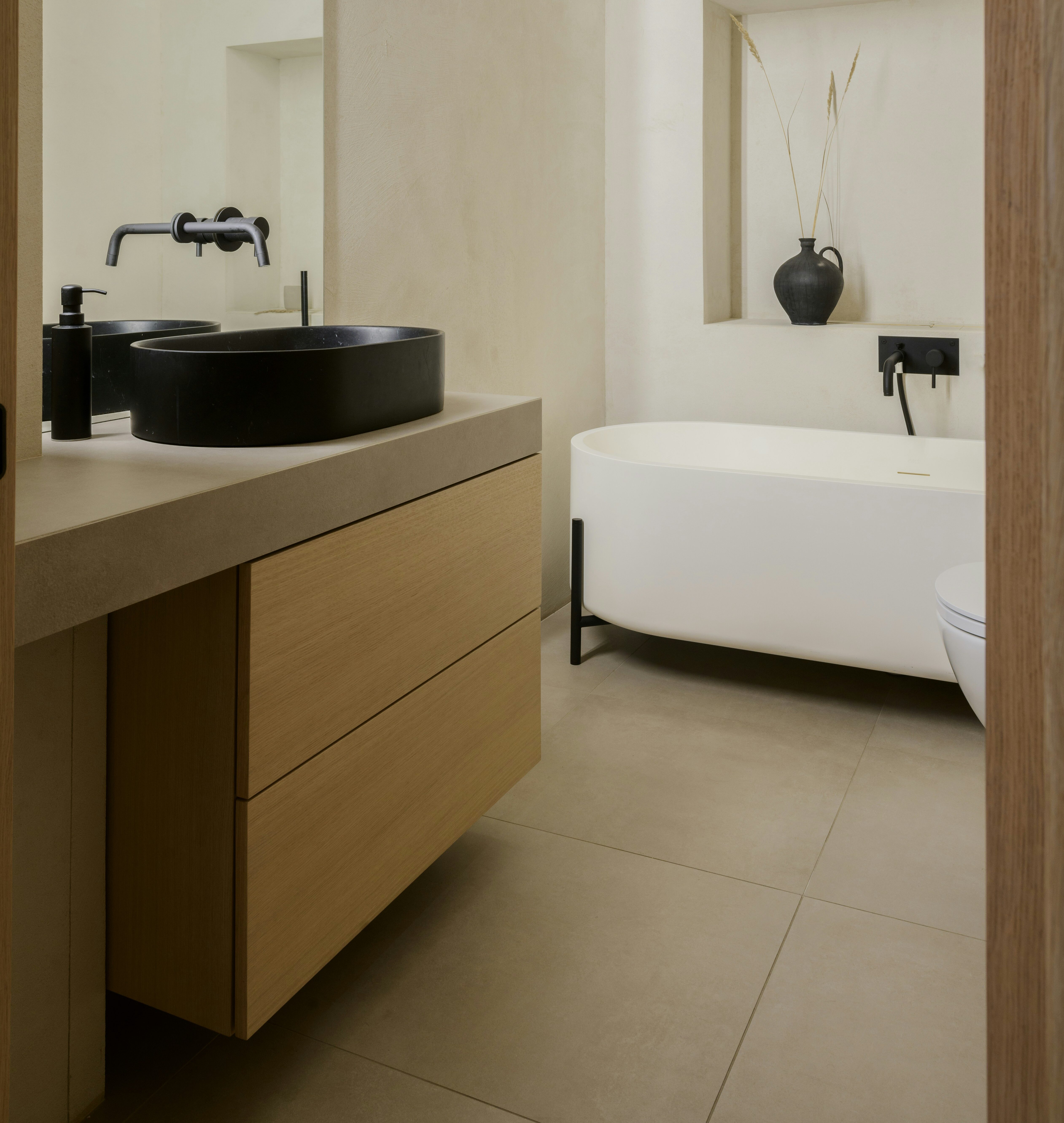 A Vessel bathroom sink sits in front of a bath tub